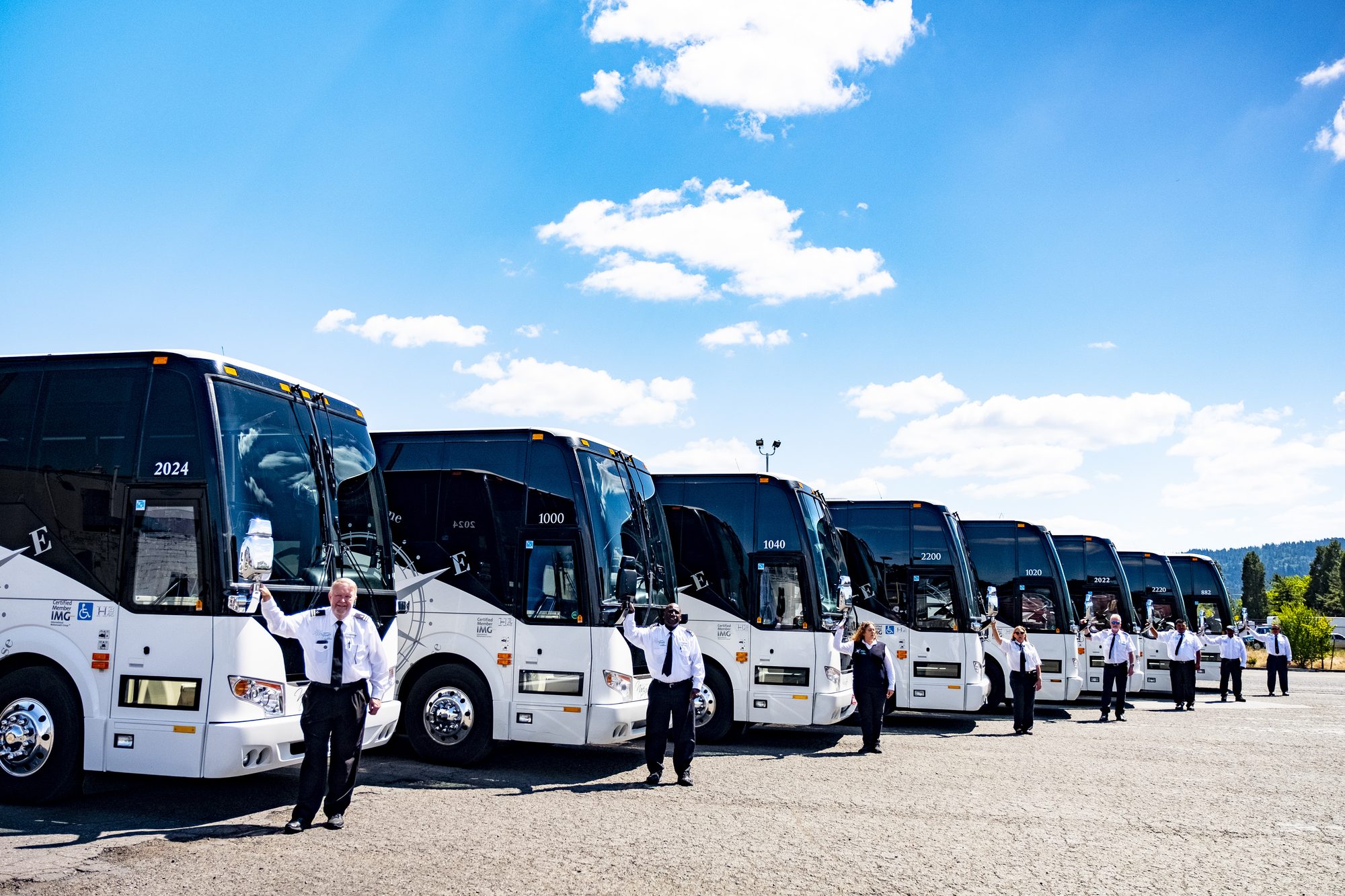NW Navigator operators standing beside a long line of coaches under a blue sky