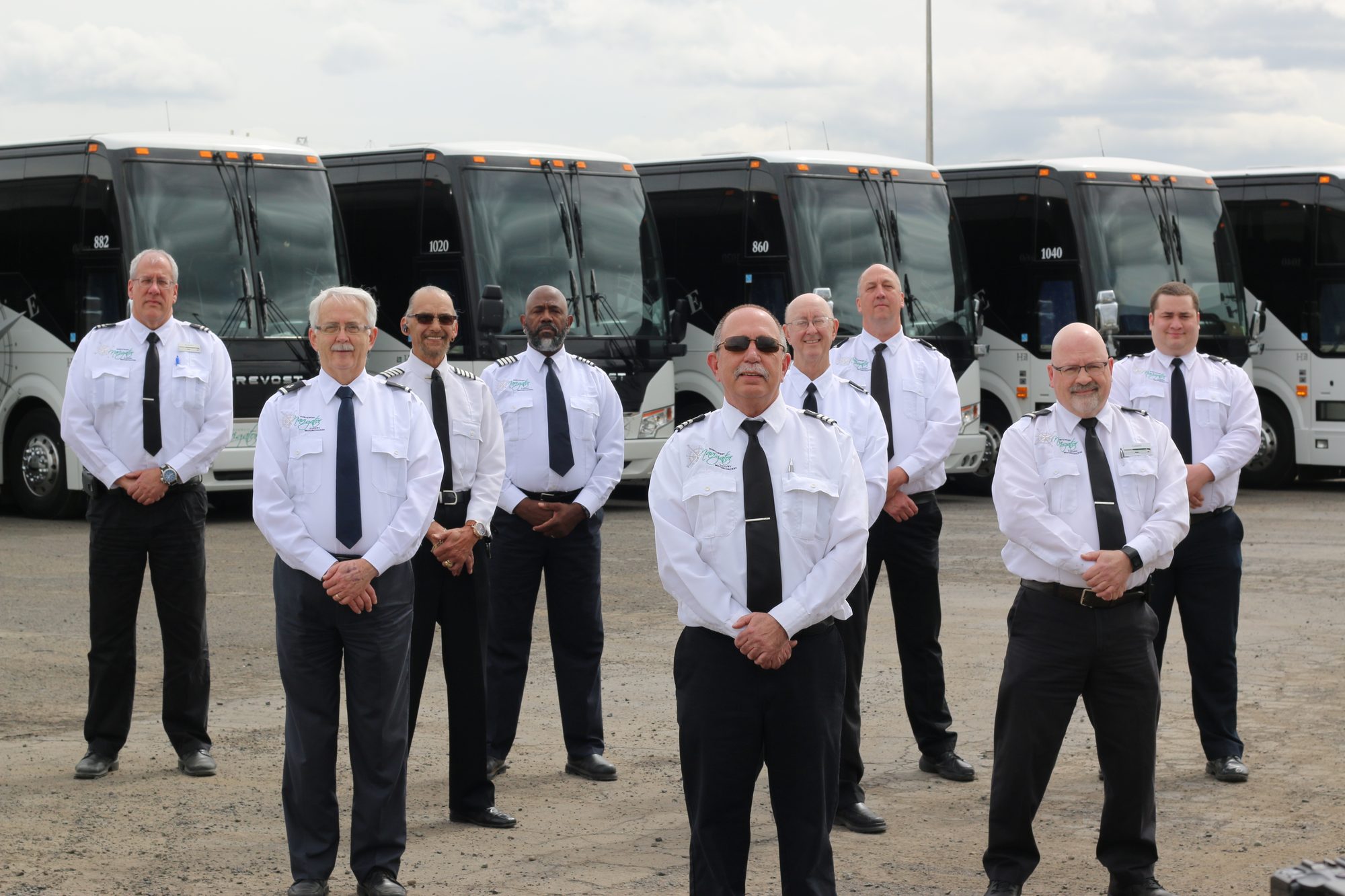 NW Navigator operators in white uniform shirts and ties, standing in front of the coach fleet
