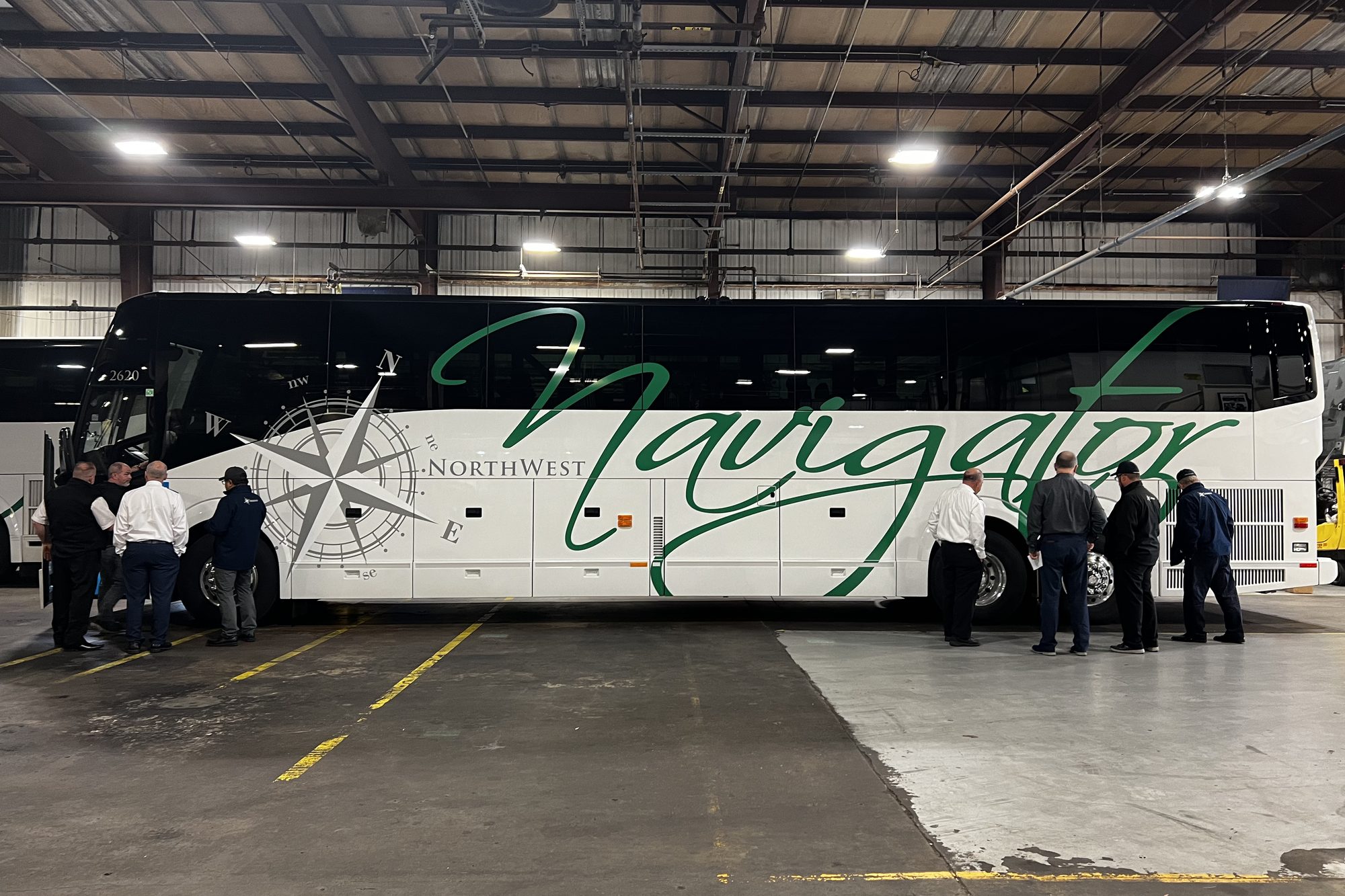 An NW Navigator coach inside the maintenance shop with technicians and staff alongside it