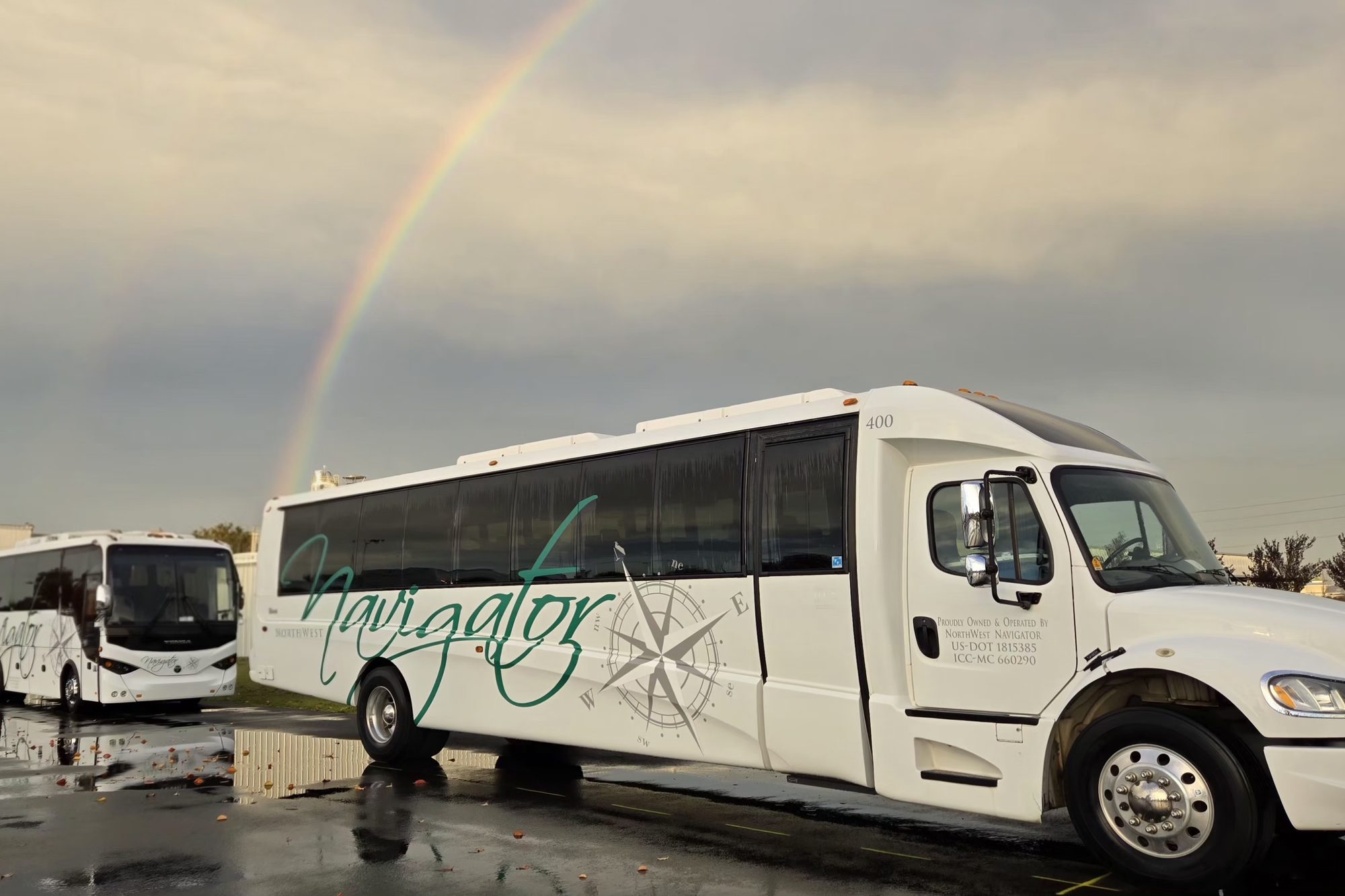 An NW Navigator mini coach and motorcoach parked under a rainbow